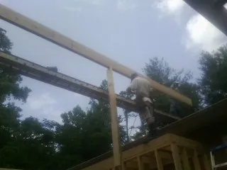 Carpenter setting a ridge beam over a new addition frame — Ice Dam Removal by Roofing Brothers in Millers Creek