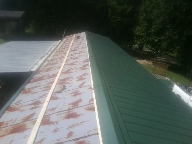 Old rusted panels beside newly installed green metal roofing — Wind Damage Roof Repair by Roofing Brothers in Millers Creek