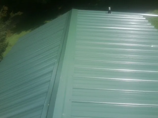 New green metal panels meeting at the ridge of a roof — Flat Roof Repair work by our crew in Millers Creek