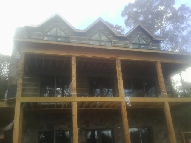 Dormers and porch framing on a large log home under construction — Roof Coating work by our crew in Millers Creek
