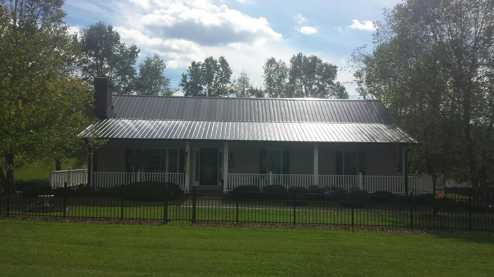 Gray metal roof on a brick ranch with a full width front porch — Gutter Guard Installation work by our crew in Millers Creek