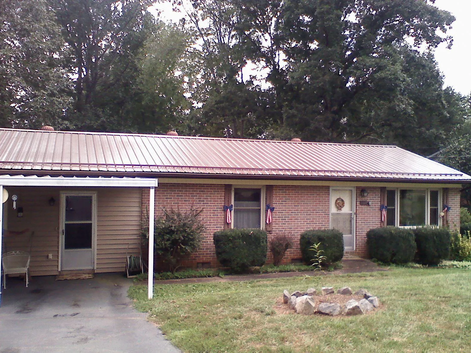 Bronze metal roof and carport on a brick ranch home — Roof Repair work by our crew in Millers Creek