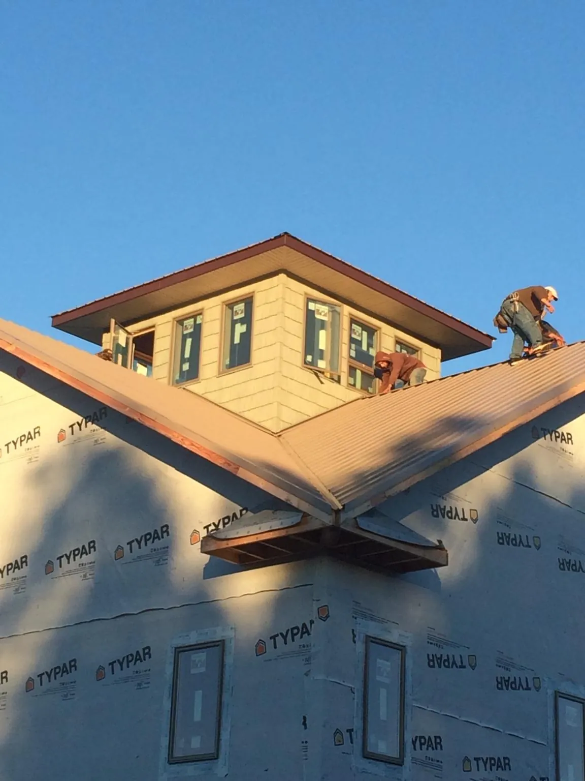 Roofers working around a rooftop cupola on a new metal roof at sunset — Roof Waterproofing in Millers Creek by Roofing Brothers